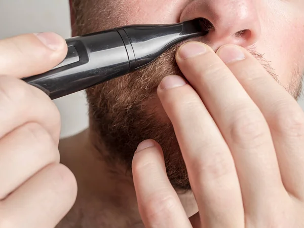 young man trimming nose hair helping himself with hands