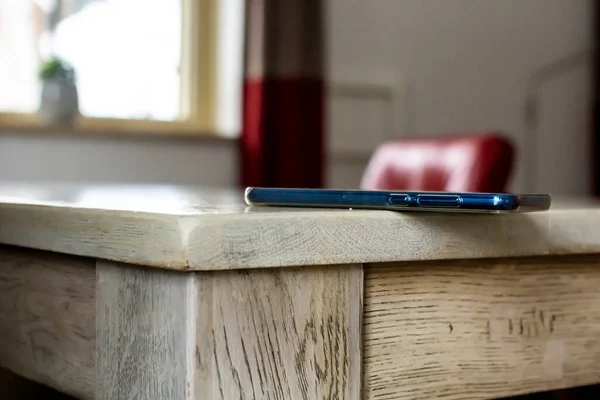 Cep Telefonu Tehlikeli Bir Şekilde Ahşap Bir Masanın Kenarında Duruyor — Stok fotoğraf