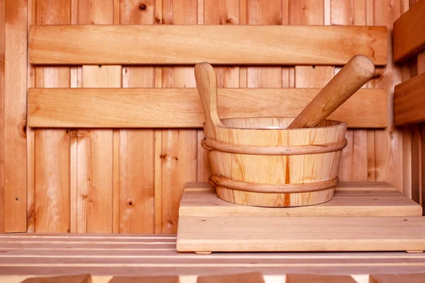 Accessories, a wooden bucket and a ladle, in a traditional Russian bath or Finnish sauna, in a cozy interior with natural materials. Close-up.