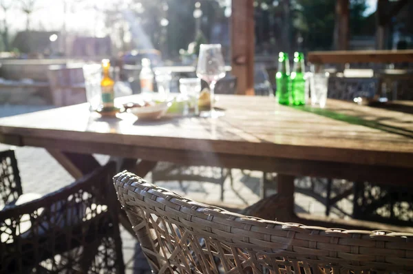 在明亮的阳光下 坐在一张木制桌子上 在街上的咖啡店里 吃喝着酒后 还留着空的脏瓶 玻璃杯 酒杯和盘子 — 图库照片