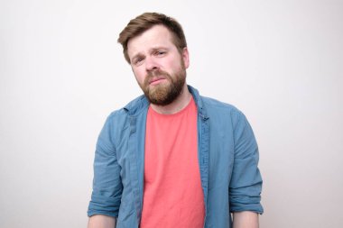 Başı ağrıyan bitkin, işkence görmüş genç bir adam gözleri kısılmış görünüyor. Beyaz arka planda izole edilmiş. Yakın plan..