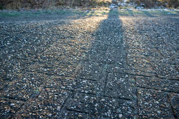 道端の背景に 春の太陽の光の中で砂利や小石と古い 着用パターンアスファルト — ストック写真