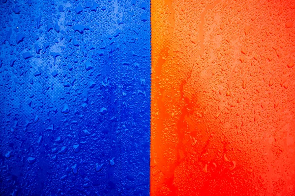 Two-tone blue-orange texture covered with droplets of water. Close-up.