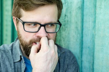 Kurnaz, hain, kötü niyetli bir şeyin portresi yan tarafa bakan, dişlerini gösteren ve elini ağzının yanında tutan bir adam. Ahşap bir duvarın arkasında. Yakın plan..