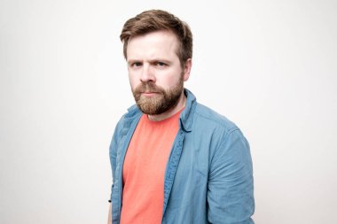 Sevimli, üzgün, sakallı adam kameraya üzgün ve kasvetli bakıyor. Beyaz arkaplanda izole.