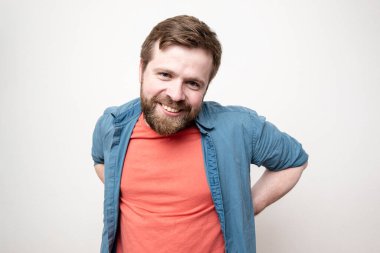 Sevimli, dost canlısı sakallı adam kameraya bakarken samimi bir şekilde gülümsüyor. Beyaz arkaplanda izole.