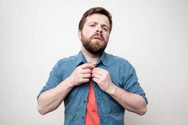 Sakallı adam gömleğine düğme takar ve gururla kameraya bakar. Beyaz arkaplanda izole.