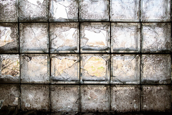 Partially broken, dirty window of glass blocks, on an abandoned farm, in the village. View from inside. Close-up.