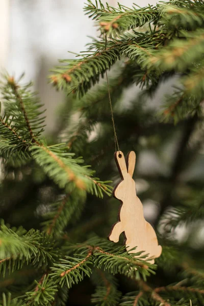かわいい木製のおもちゃ クリスマスツリーのウサギ 緑の枝のぼやけた背景 — ストック写真
