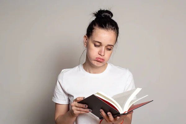 Die Junge Hübsche Studentin Blickt Traurig Ein Aufgeschlagenes Buch Und — Stockfoto