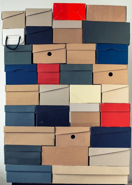 Pile of evenly folded shoe boxes against a white wall. Seasonal sales and discounts. Vertical photo.
