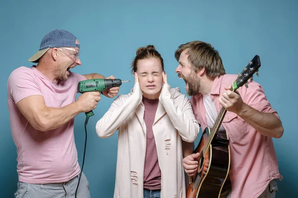 Una desafortunada mujer cubrió los oídos para no escuchar a un vecino tocar la guitarra, y al otro trabajando con un taladro eléctrico. Estrés . —  Fotos de Stock