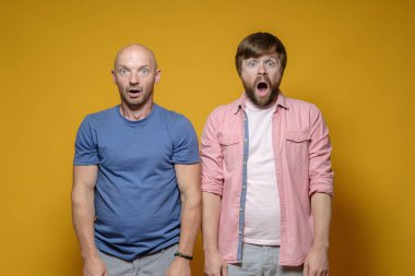 Şaşırmış iki adam şok içinde ağızlarını açar ve şaşkınlıkla kameraya bakar.. 