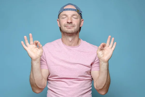 Lindo hombre muestra buen gesto con dos manos y se para tranquilamente con los ojos cerrados. Todo está bien.. — Foto de Stock