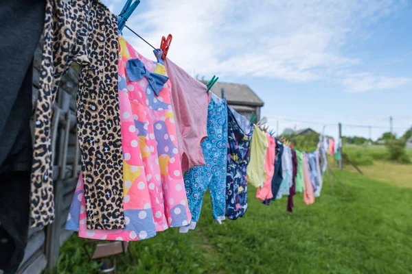 Saubere, gewaschene Kleidung wird draußen im Dorf an einem Seil mit Wäscheklammern getrocknet. Lebensstil. — Stockfoto