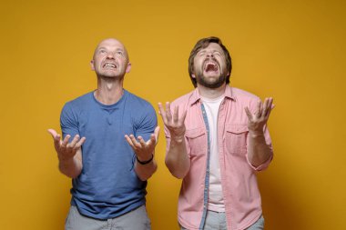 İki adam ellerini kaldırıp sorgulayıcı bir jest yapıyor. Acı çekiyor ve bağırıyorlar. Neden bu kadar mutsuz olduklarını anlamıyorlar..