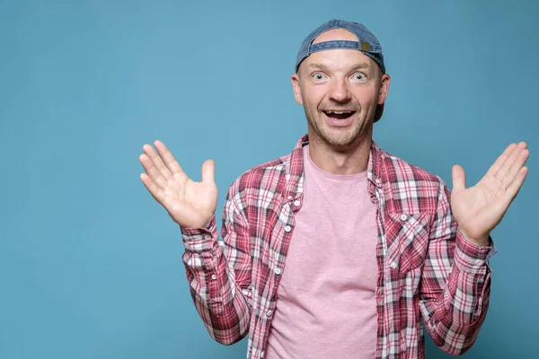 Funny man in a cap threw up hands in surprise, he is glad for a pleasant surprise, opened mouth in shock and looks with big eyes. — Stock Photo, Image