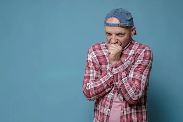 El hombre con gorra y camisa está congelado, se envuelve en ropa y se calienta las manos con el aliento. Copiar espacio. concepto de temporada de calefacción. — Foto de Stock