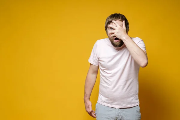 Bang, verbaasd man bedekt gezicht met de hand, opende de mond in shock en keek met één oog naar de camera. Kopieerruimte. — Stockfoto