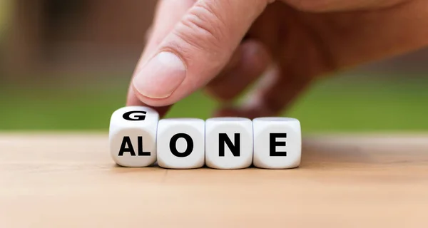 Hand turns a dice and changes the word "gone" to "alone". — Stock Photo, Image