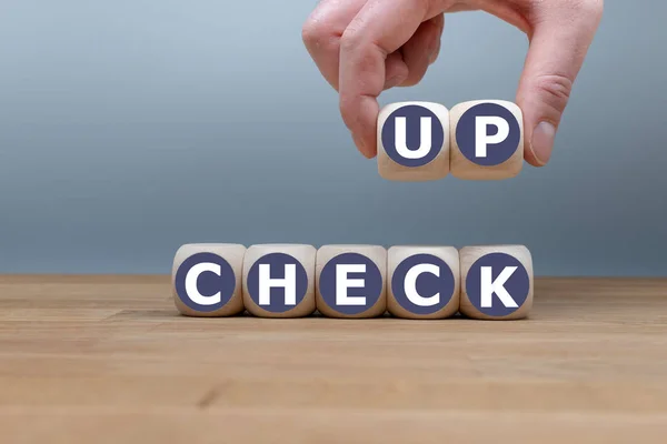 Kości tworzą słowo "check up", podczas gdy ręka podnosi litery "up — Zdjęcie stockowe