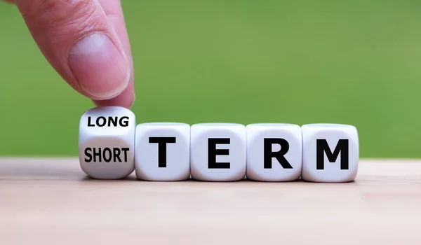 Hand turns a dice and changes the expression "SHORT TERM" to "LO — Stock Photo, Image