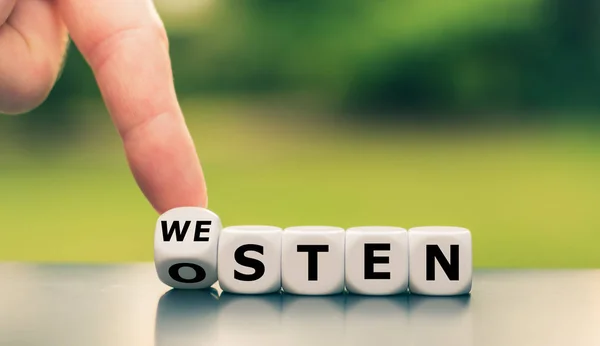 Hand dreht einen Würfel und ändert das deutsche Wort "osten" ("Osten") in — Stockfoto