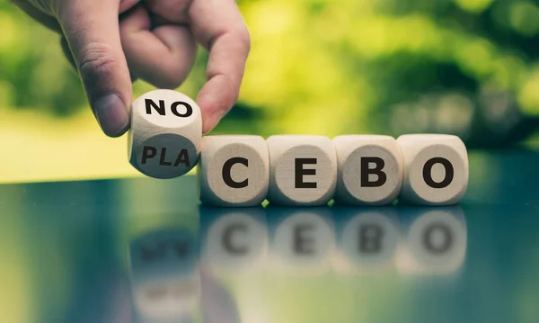 Nocebo or placebo? Hand turns a cube and changes the word "place — 스톡 사진