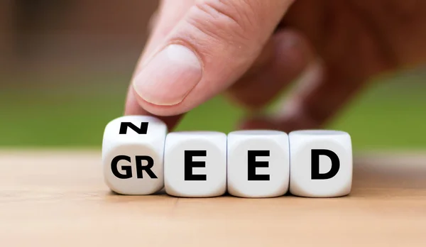 Need or Greed? Hand turns a dice and changes the word "Greed" to — ストック写真