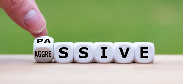 Hand draait een dobbelsteen en verandert het woord "passief" in "agressief" — Stockfoto