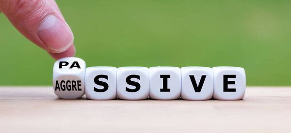 Hand turns a dice and changes the word "passive" to "aggressive"