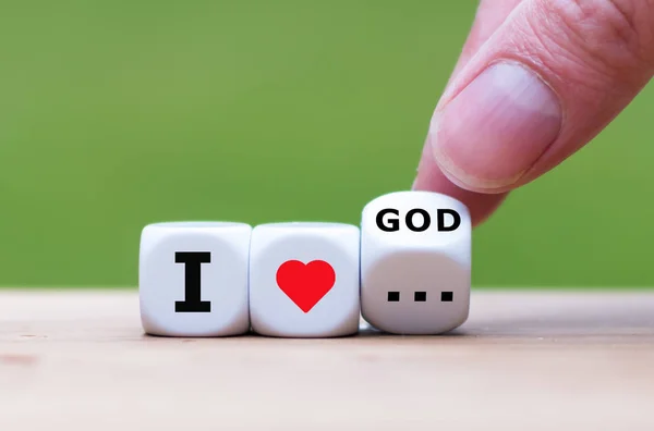 Hand turns a dice and changes the expression "I love god" to "I — Stock Photo, Image