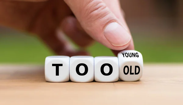 Hand turns a dice and changes the expression "too old" to "too y — 스톡 사진