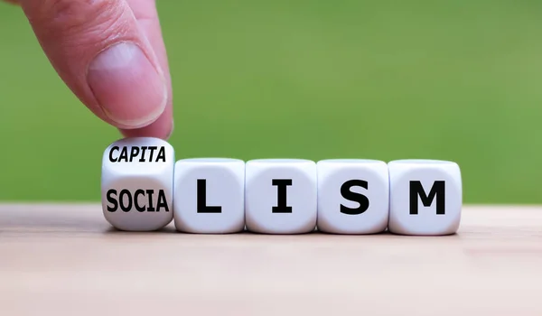 Hand flips a dice and changes the word "Socialism" to "Capitalis — Stock Photo, Image