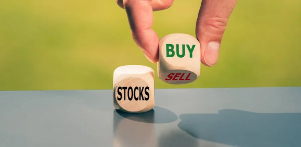 Sprzedajesz czy kupujesz akcje? Ręka obraca kostkę i zmienia słowo — Zdjęcie stockowe