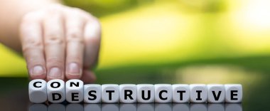 Hand turns dice and changes the word destructive to constructive. clipart