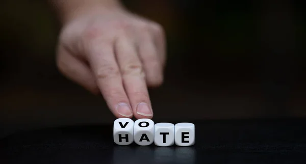 Vote instead of hate. Hand turns dice and changes the word \