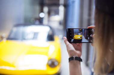 Mobil telefon ve bir araba resimlerini alır tutan el