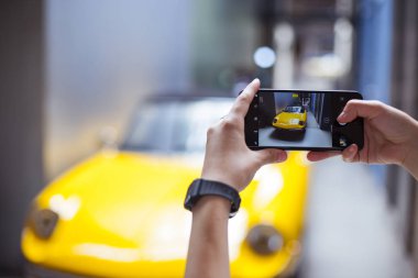 Mobil telefon ve bir araba resimlerini alır tutan el