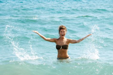 Gülümseyen güzel genç kadın denizde ayakta