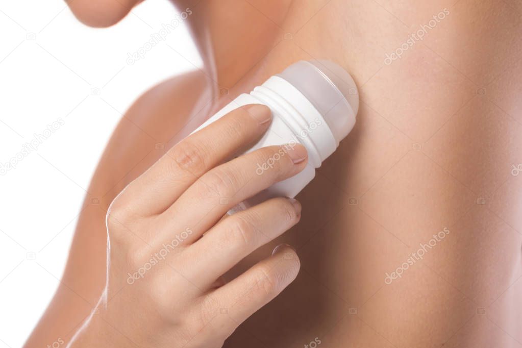 Woman applying deodarant on her armpit on white background