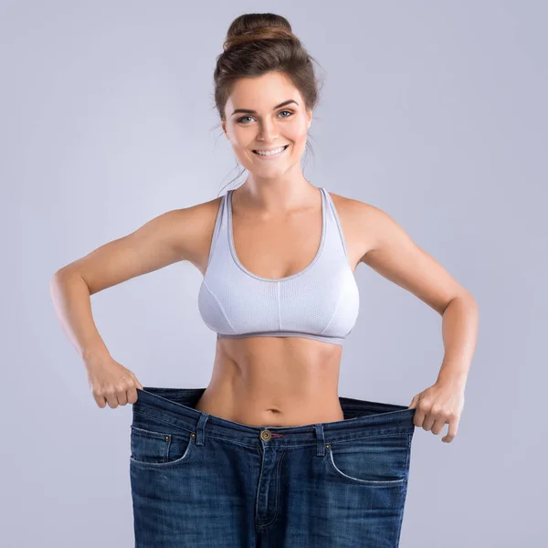 Happy woman after weight-loss is try her old jeans
