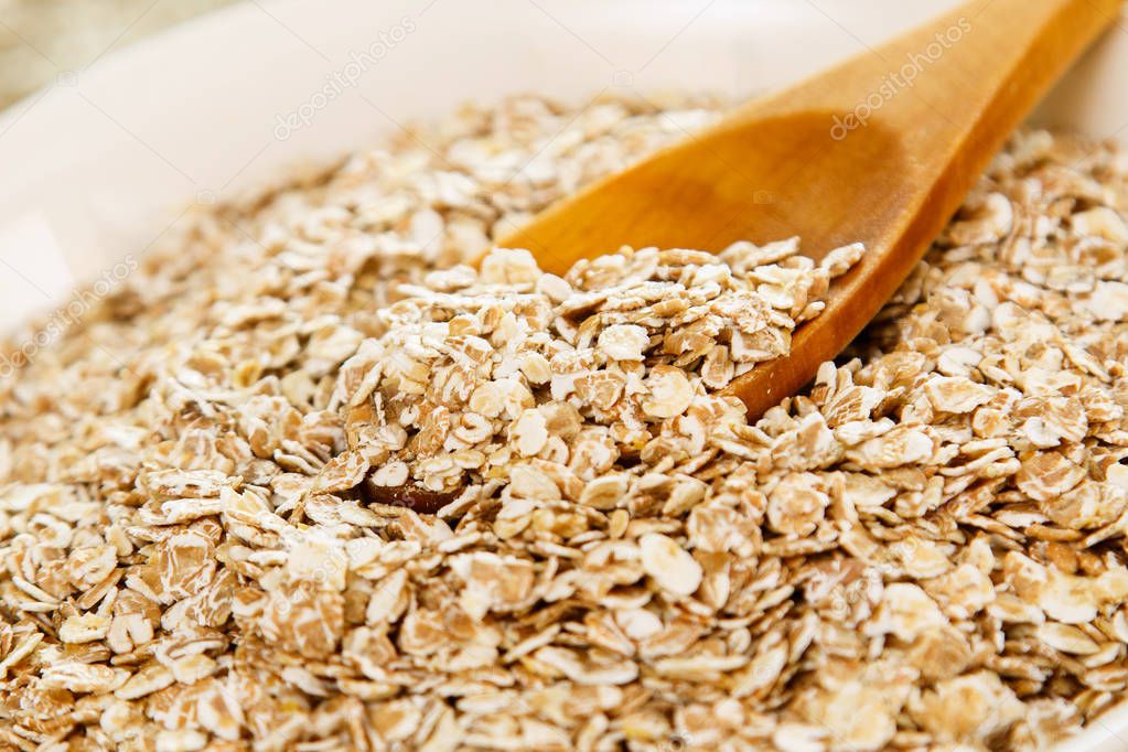 Uncooked oatmeal and wooden spoon. The best grain for breakfast.