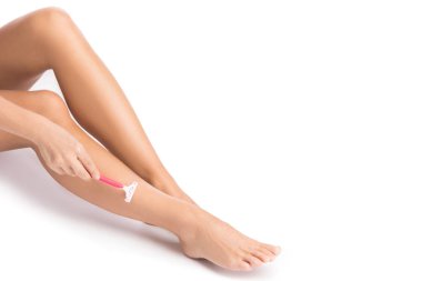 Kadın bacakları ve beyaz arka planda tıraş bıçağı.