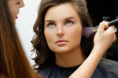 Kozmetik uygulama modeli yüzünde makyaj sanatçısı