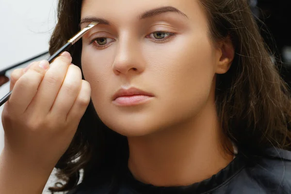 Makeup artist applying cosmetics on model face