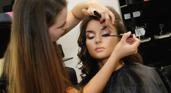 Makeup artist applying cosmetics on model face