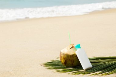 Kumsalda güneş losyonu ve Hindistan cevizi içmek