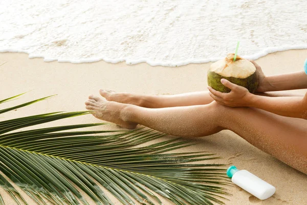 Plaj kavramı üzerinde rahatlatıcı. Kadın bacaklar, Hindistan cevizi ve güneş kremi losyon