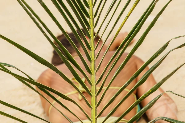 Palmiye yaprağı kumlu plaj arka plan üzerinde yatan genç kadınla